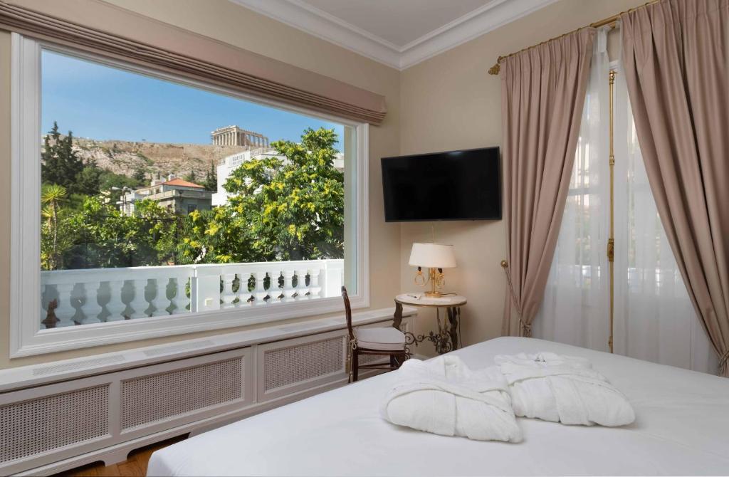 a bedroom with a bed and a large window at Noble Suites in Athens