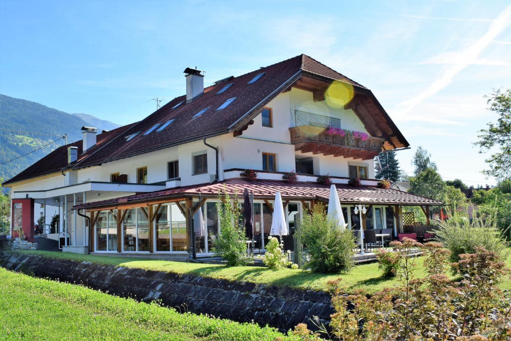 a large white house with a roof at Frühstücks-Radpension Taurer-Thoman in Dellach im Drautal