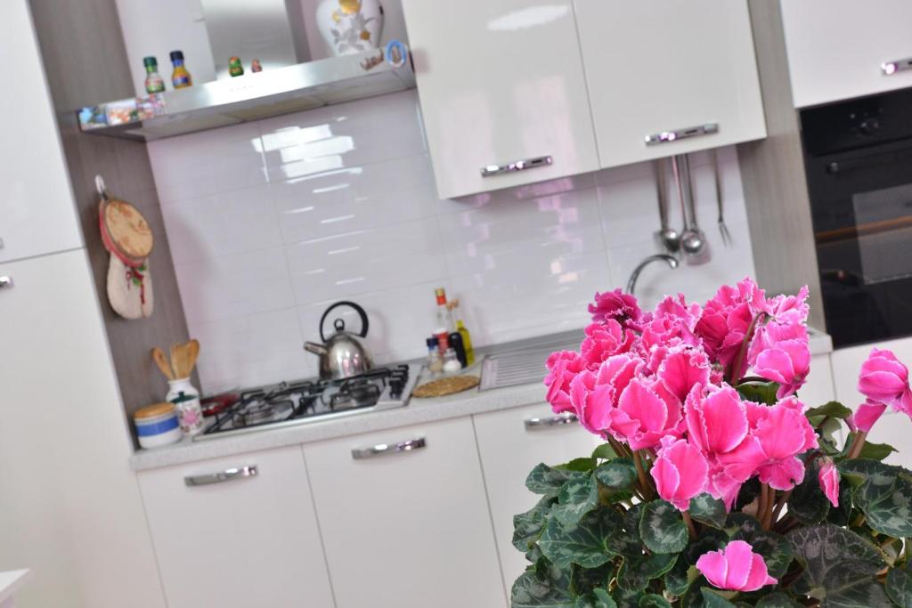eine weiße Küche mit rosa Blumen in einer Vase in der Unterkunft IzzHome Regina Margherita in Pula