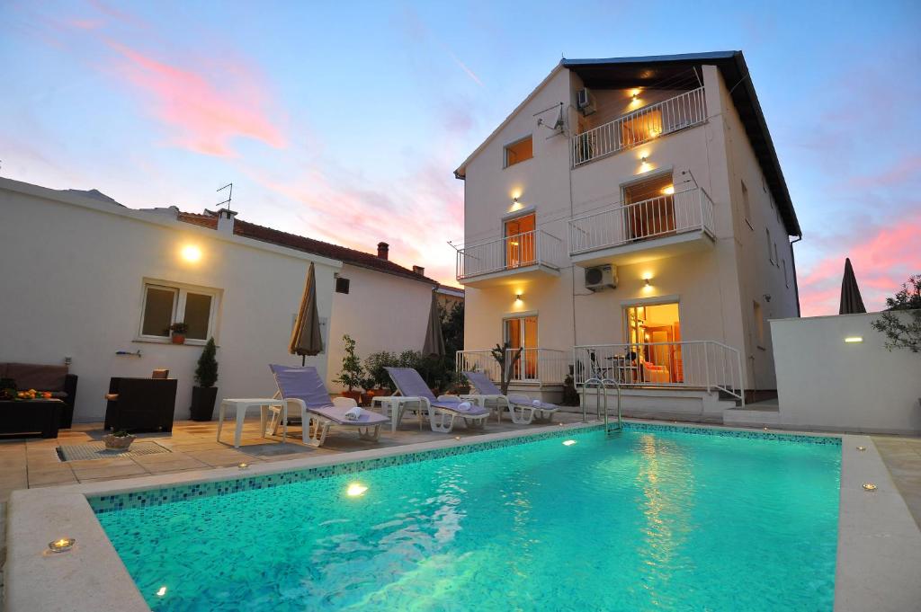 a villa with a swimming pool in front of a house at Apartments Batur in Zadar