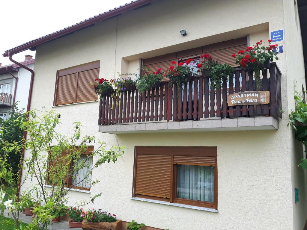 a building with a balcony with flowers on it at Apartman Petra & Tena in Slunj