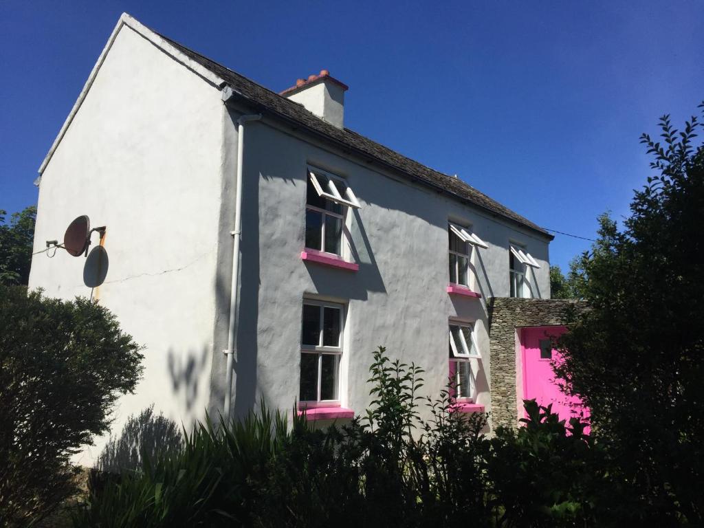 a white house with pink doors and windows at Boss’s farmhouse in Valentia Island