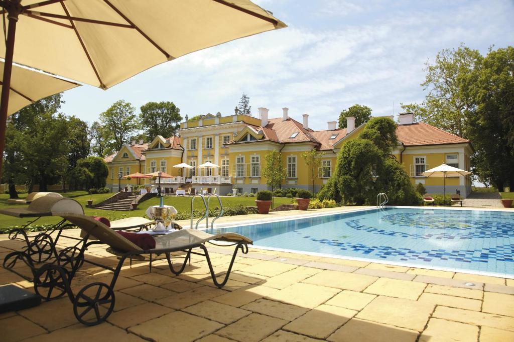 a large house with a swimming pool and an umbrella at Hertelendy Kastély Exclusive in Kutas