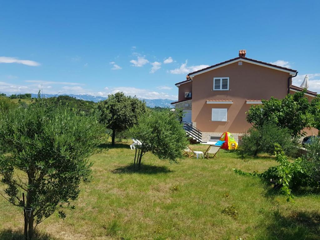 a house with a yard with trees in front of it at Apartments Mestrovic in Lopar