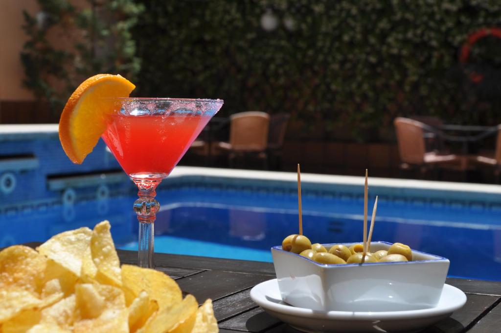 een drankje en chips op een tafel naast een zwembad bij Hotel Mar de Tossa in Tossa de Mar