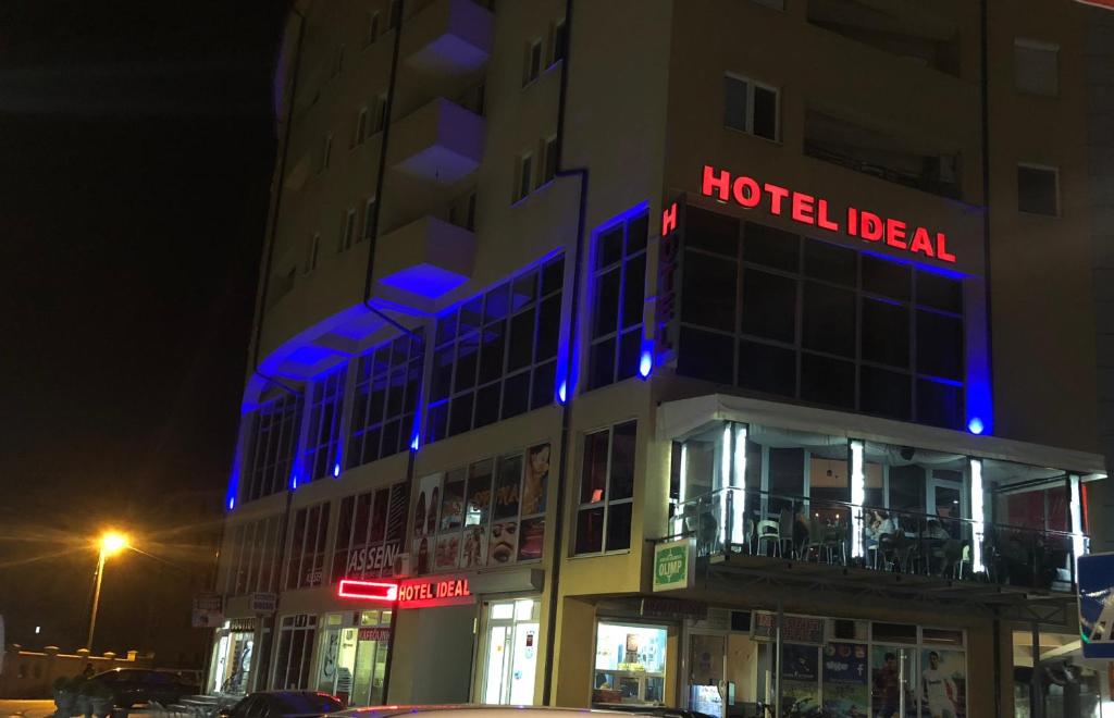 a hotel building with a blue neon sign on it at Ideal city in Tutin
