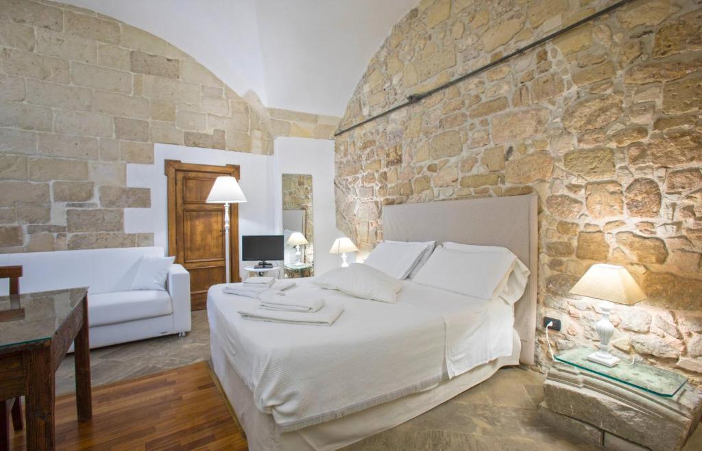 - une chambre avec un grand lit et un mur en pierre dans l'établissement Chiesa Greca - SIT Rooms & Apartments, à Lecce