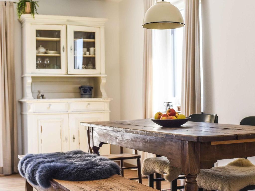 uma sala de jantar com uma mesa de madeira e uma taça de fruta em Ferienwohnung im Weiler em Winterlingen