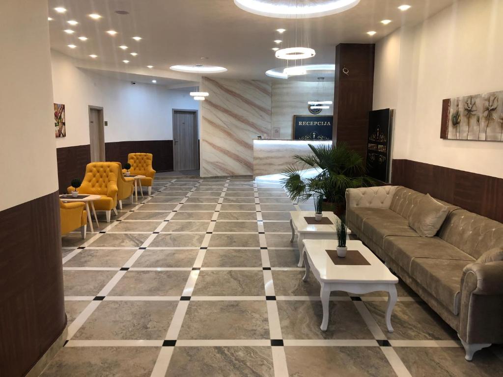 a lobby with a couch and tables and chairs at Ideal city in Tutin