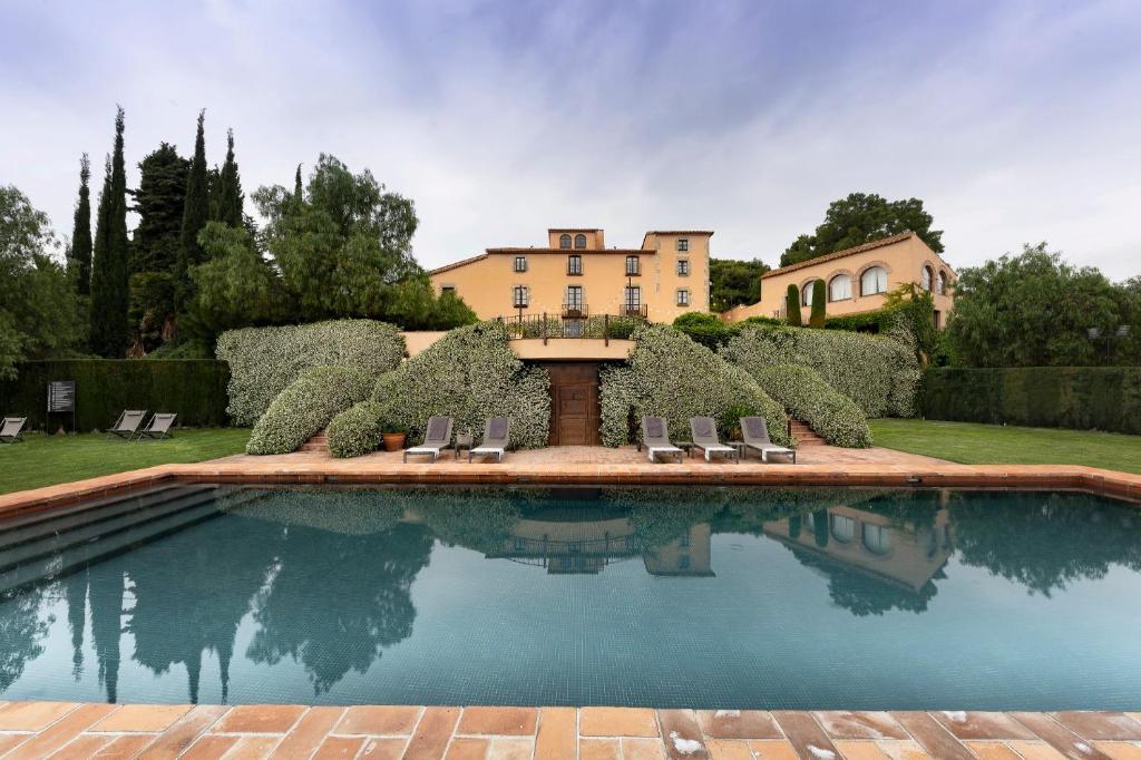 a swimming pool with chairs and a house in the background at Can Mora de Dalt in Sant Vicenç de Montalt