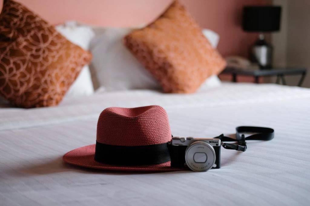 un cappello e una telecamera su un letto di H Hotel Phrasing a Chiang Mai