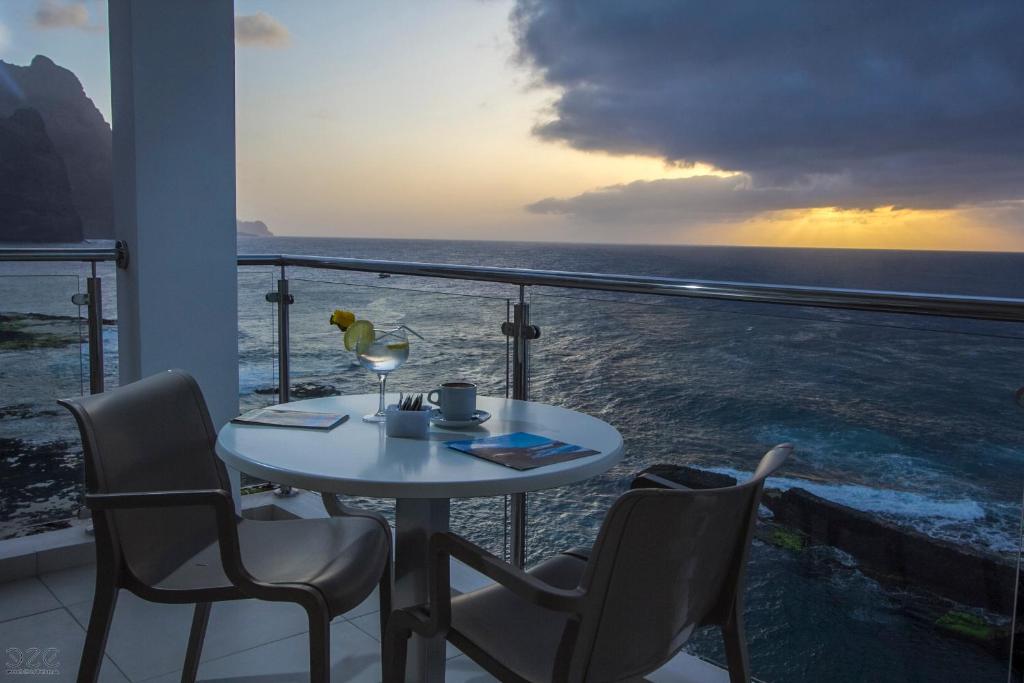 uma mesa e cadeiras numa varanda com vista para o oceano em Tiduca Hotel em Ponta do Sol