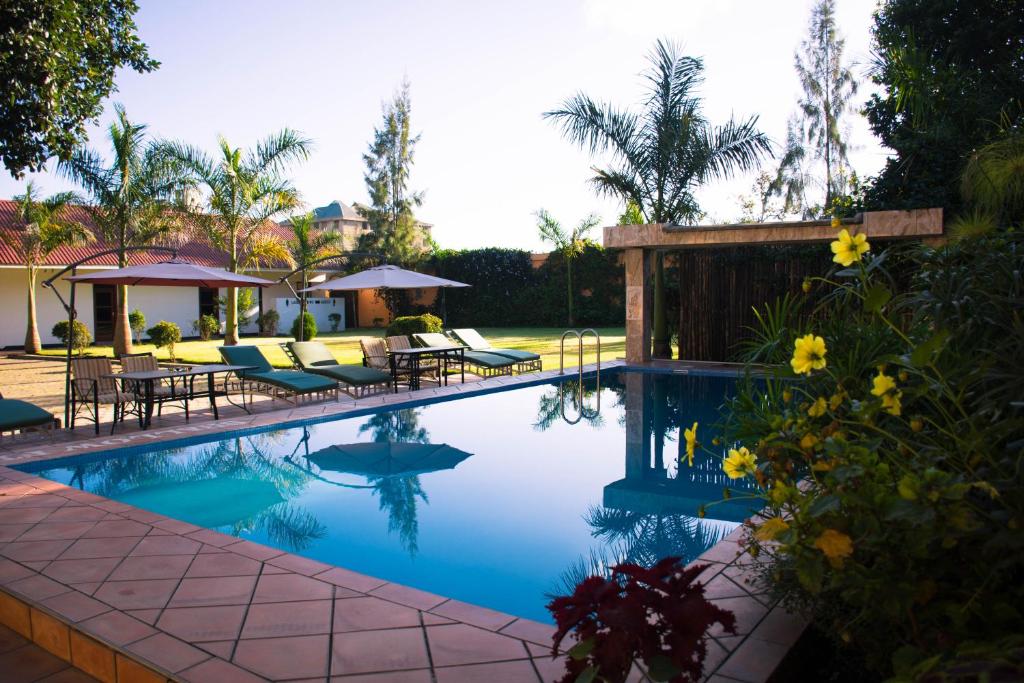 - une piscine avec des tables et des chaises dans la cour dans l'établissement Tulia Boutique Hotel & Spa, à Arusha