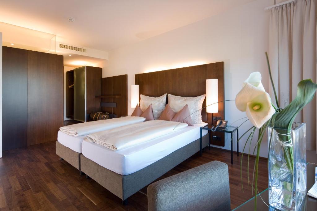 a bedroom with a large bed and a vase with a flower at Hotel Penz West in Innsbruck