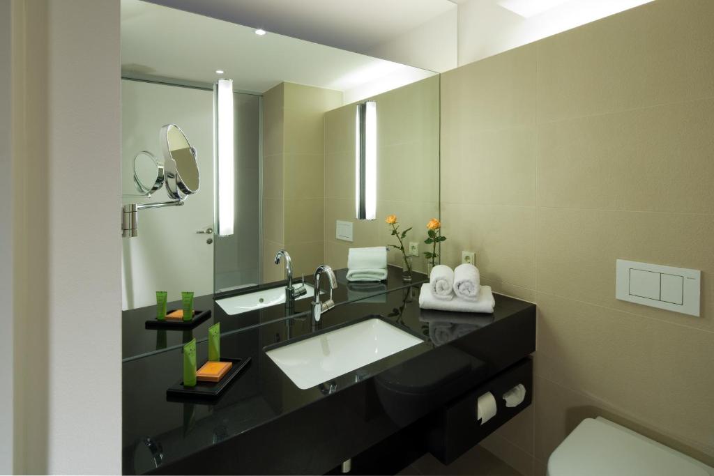 a bathroom with two sinks and a large mirror at Hotel Penz West in Innsbruck