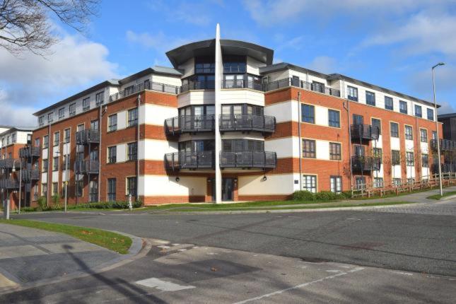 a large brick building with a balcony on a street at Blue Sky Apartments @Wallis Square, Farnborough in Farnborough