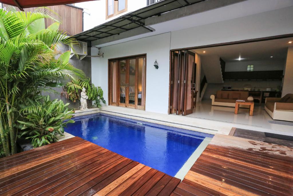 a swimming pool in front of a house at Nyoman Villa Sanur in Sanur