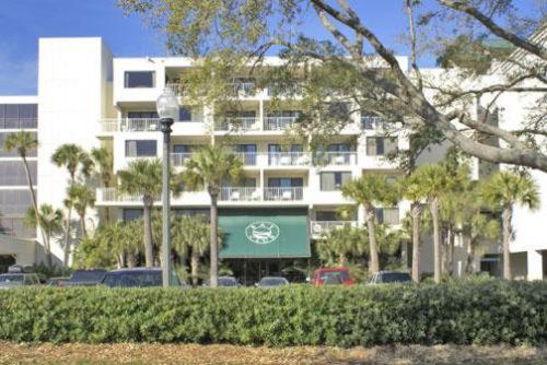 un grand bâtiment blanc avec des palmiers devant lui dans l'établissement Bay Club of Sandestin, a VRI resort, à Destin