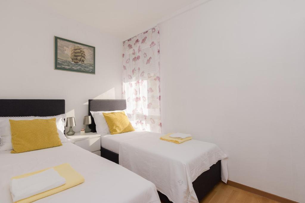 Duas camas num quarto com paredes brancas e almofadas amarelas em Barita em Zadar