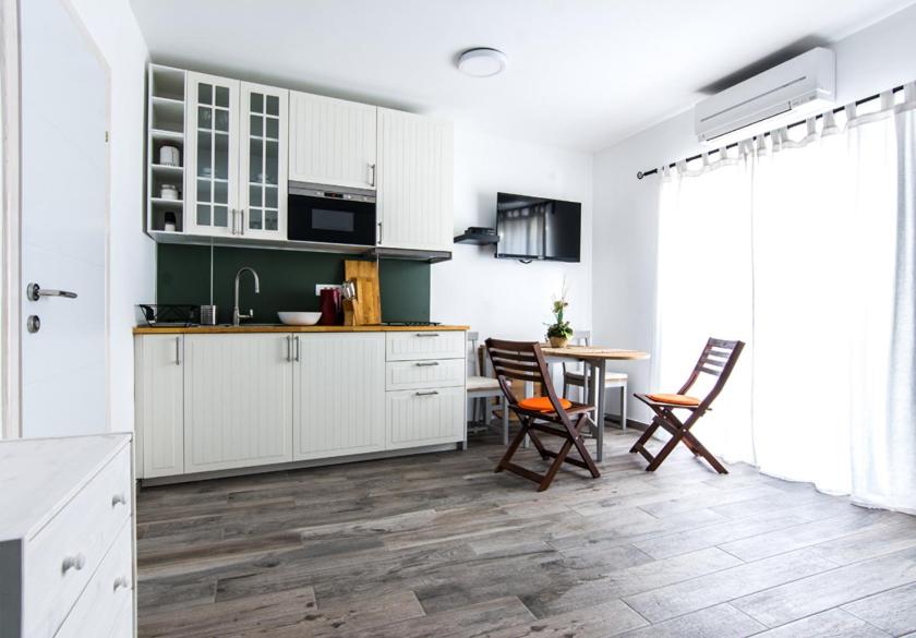 a kitchen with white cabinets and a table and chairs at Apartments Jankovic in Biograd na Moru