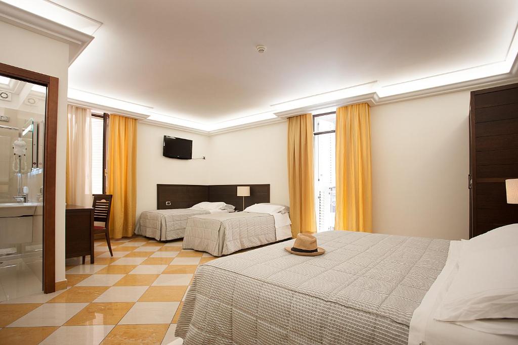a hotel room with two beds and a kitchen at Albergo del Golfo in Naples
