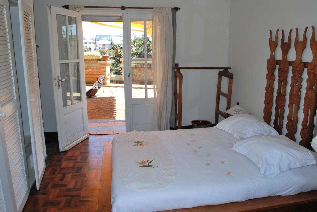 sypialnia z łóżkiem i drzwiami prowadzącymi na patio w obiekcie Appartements d'Hôtes Marciloui w mieście Antsirabe
