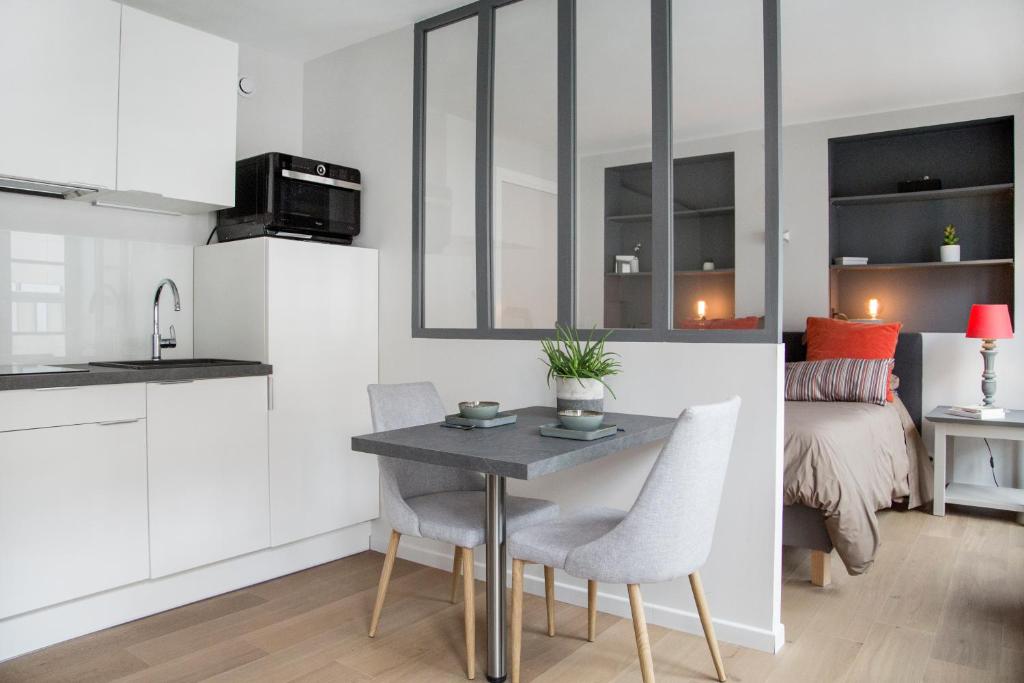 cocina y sala de estar con mesa y sillas en Stay Appart Hotel Lille Centre en Lille