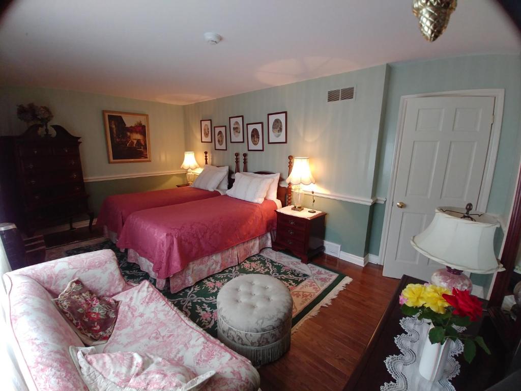 a bedroom with a red bed and a couch at TwiningRetreat in Niagara-on-the-Lake