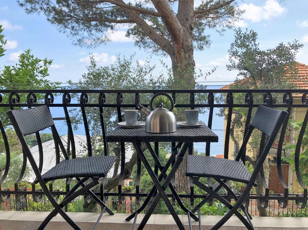 a table and chairs with a tea kettle on a balcony at House Levante by Holiday World in Pieve Ligure