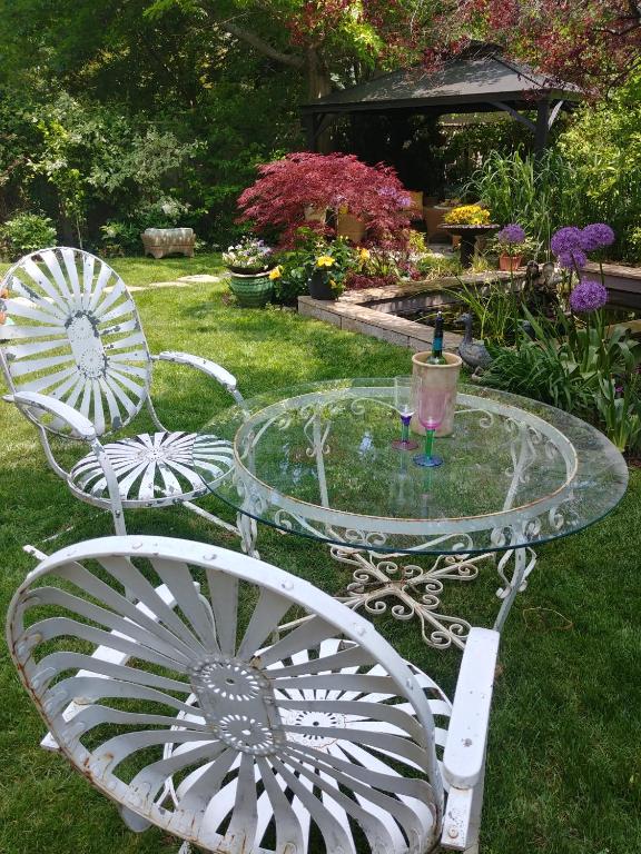 a glass table and two chairs in a yard at TwiningRetreat in Niagara-on-the-Lake