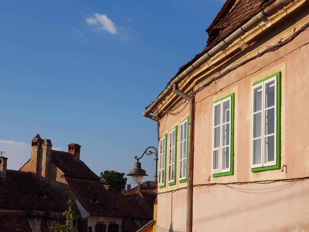 a building with green windows and a bell on it at Santino Apartment in Sibiu