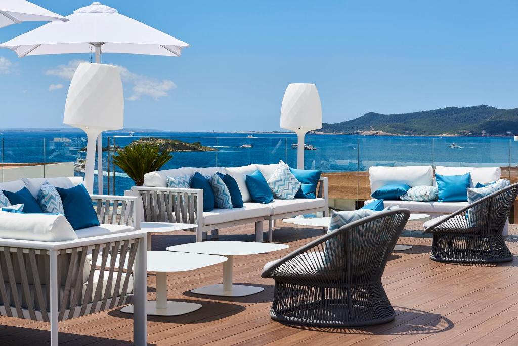 un patio con sofás, sillas y una sombrilla en Eurostars Ibiza en Ibiza