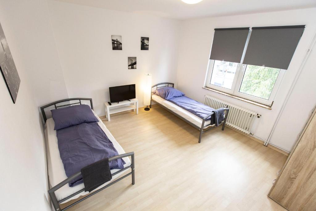 ブレーマーハーフェンにあるAVR Apartment Geestemundeのベッド2台とテレビが備わる客室です。