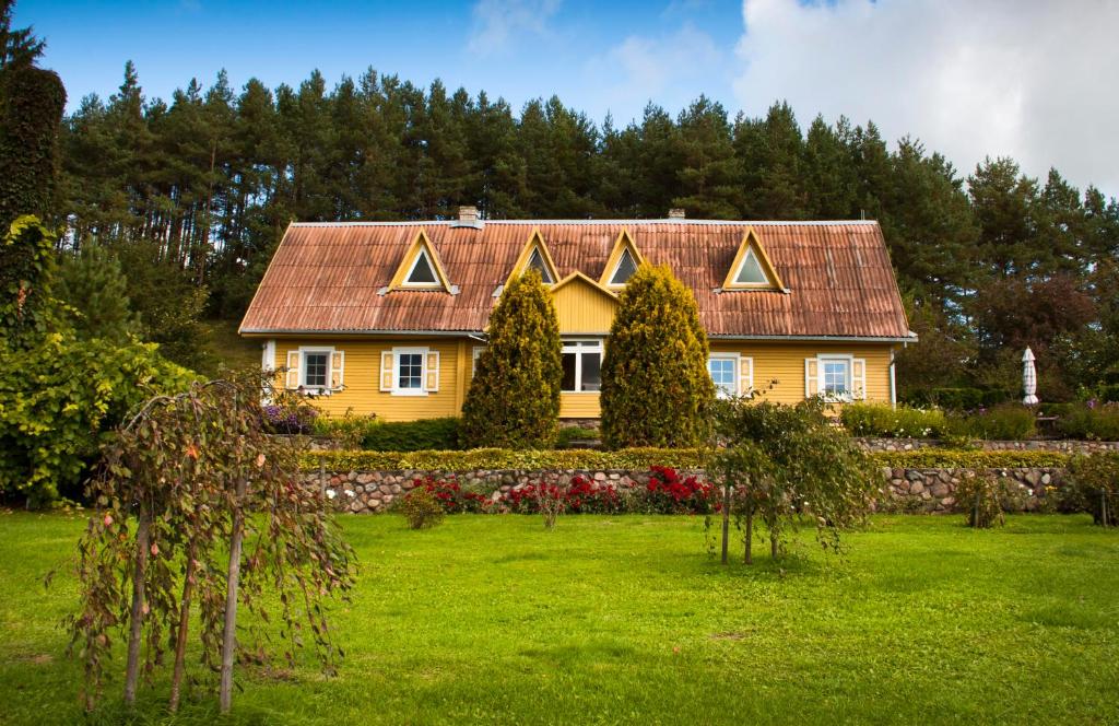 uma casa amarela com um telhado vermelho num quintal em Sodyba Dubinga em Molėtai