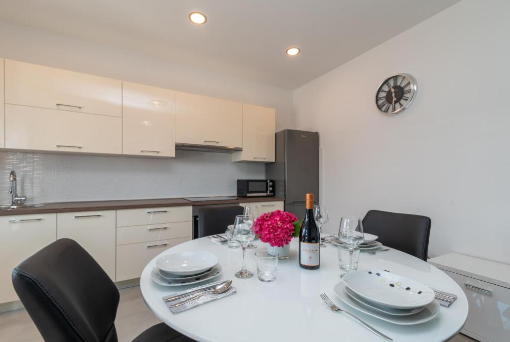 特羅吉爾的住宿－Apartment Matea，白色的厨房配有桌椅和一瓶葡萄酒