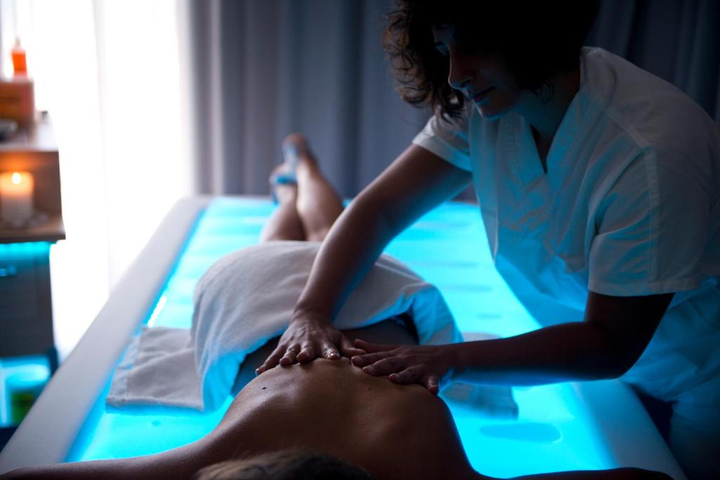 a woman giving a man a massage on a bed at Grand Hotel Masseria Santa Lucia in Ostuni