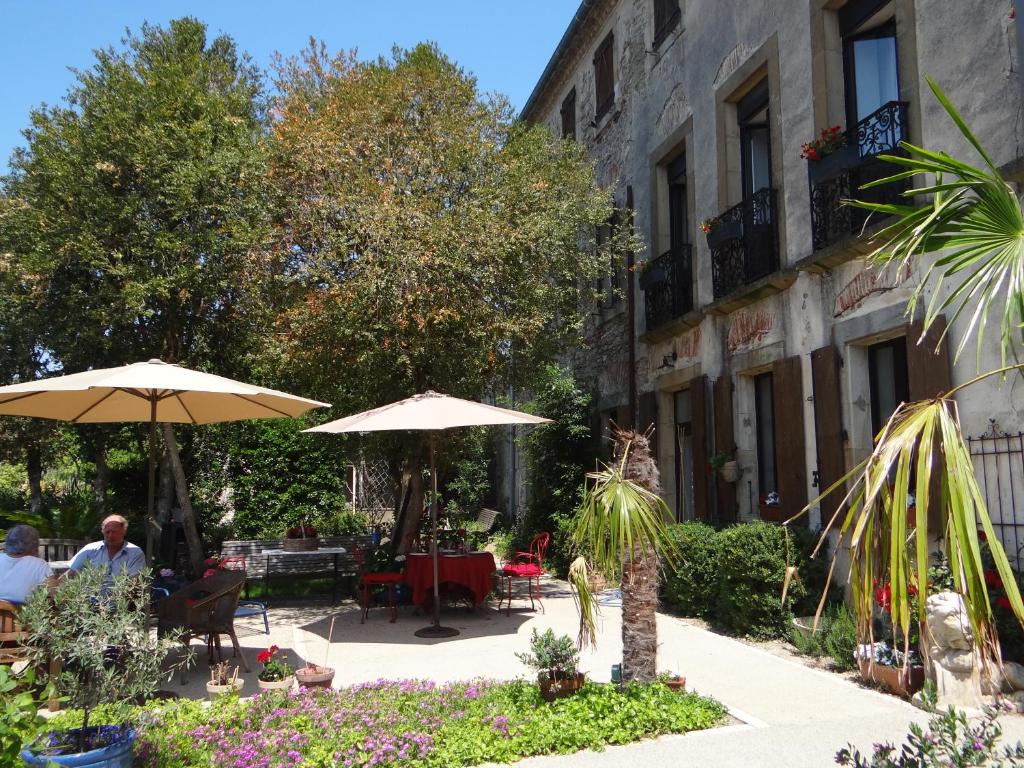 un patio avec des tables et des parasols et un bâtiment dans l'établissement La Grande Maison, à Cambieure