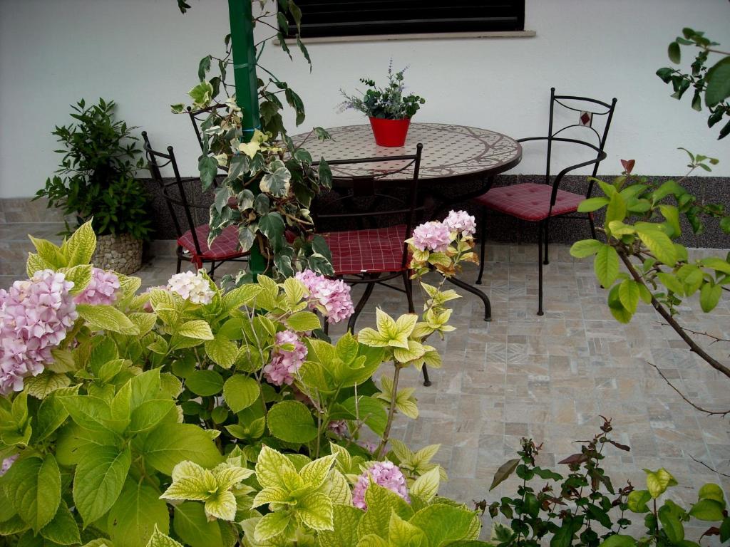 patio ze stołem, krzesłami i kwiatami w obiekcie Apartman Lucija w mieście Kaštela