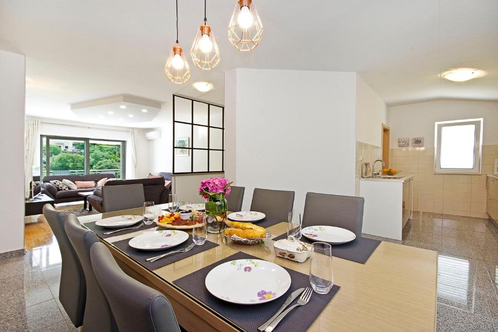 a dining room and living room with a table and chairs at Luxurious, modern and spacious apartment with terraces in Tugare