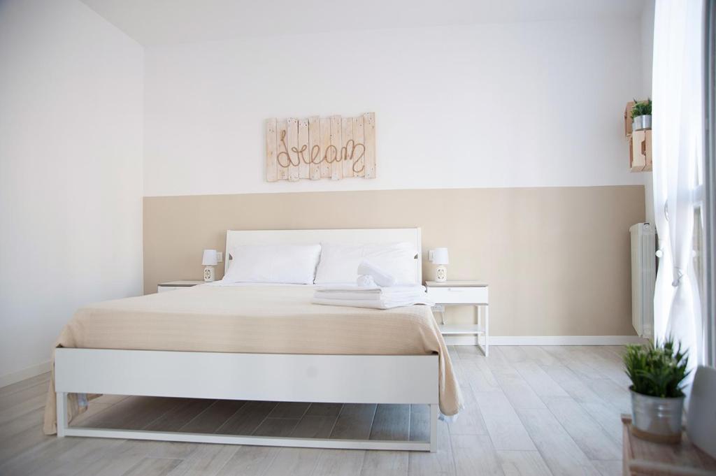 a white bedroom with a bed and a table at Le Mura apartment in Peschiera del Garda