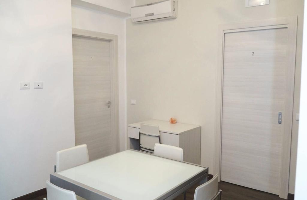 una sala da pranzo bianca con tavolo e sedie bianchi di La Perla Del Sole a Corigliano Calabro