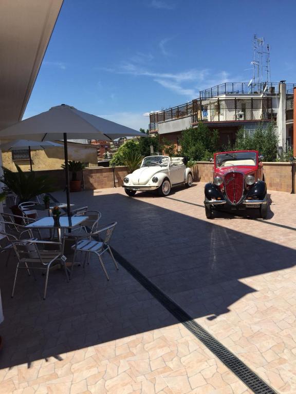 dois carros velhos estacionados ao lado de uma mesa com um guarda-chuva em Beb la lupa em Roma