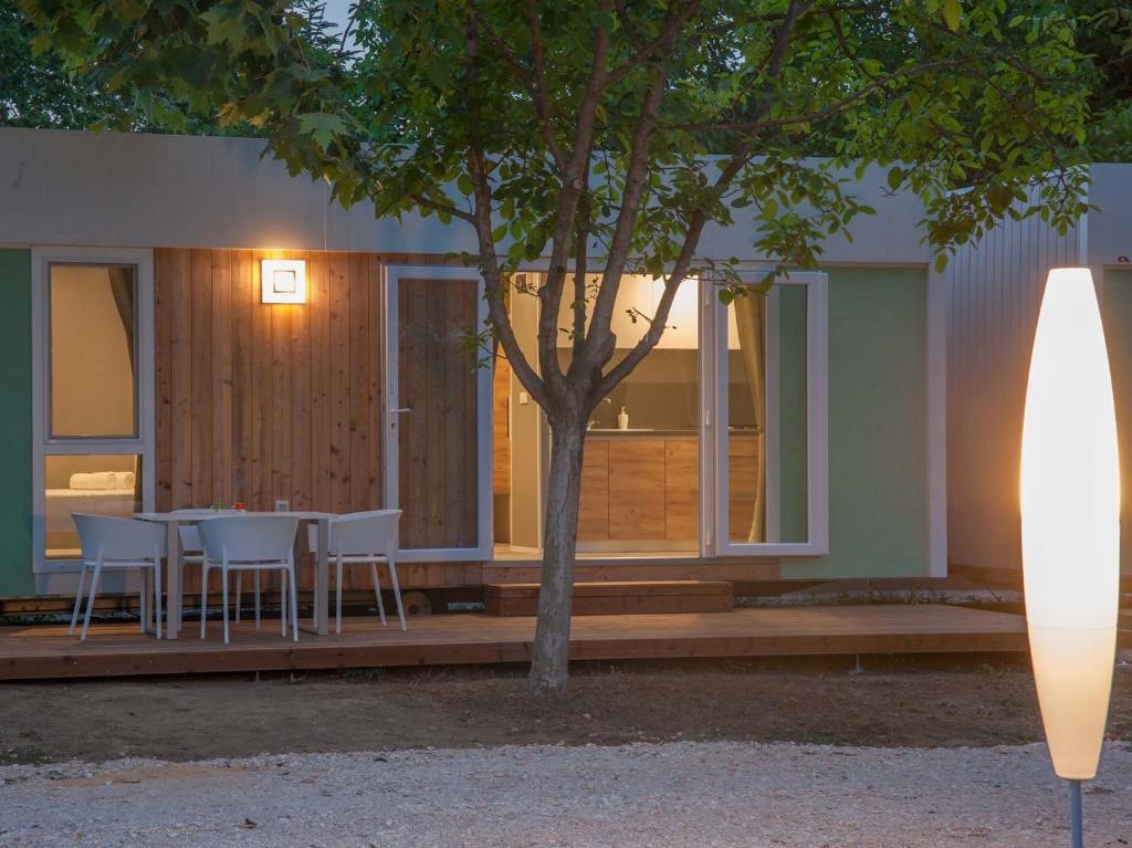 a house with a table and chairs on a deck at Aurora Camping and Mobile Homes in Paralia Panteleimonos