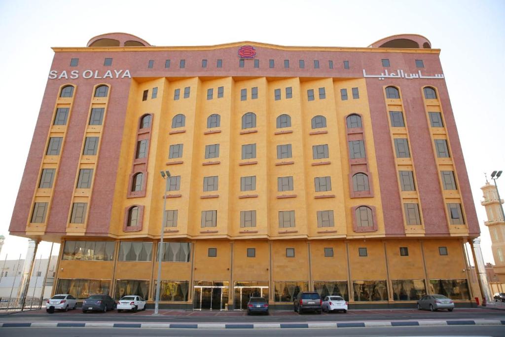 un gran edificio amarillo con coches estacionados frente a él en SAS Al Olaya Hotel Suites, en Al Khobar