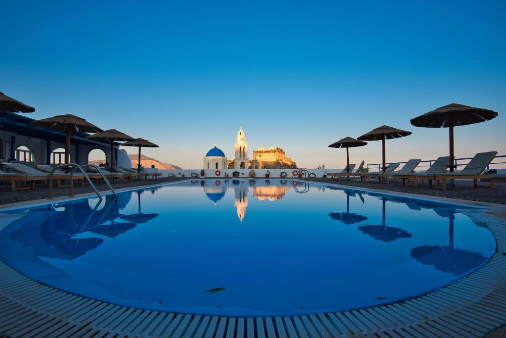 a swimming pool with chairs and umbrellas at dusk at Thira's Dolphin in Akrotiri
