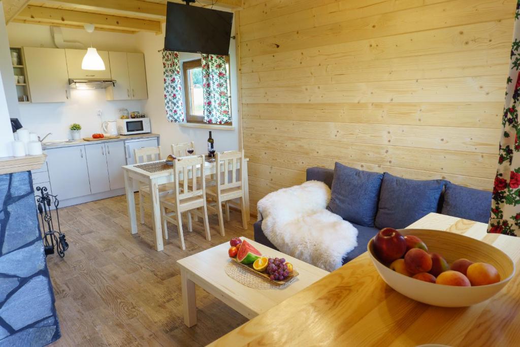 a living room with a couch and a bowl of fruit on a table at Domki u Huberta in Grywałd