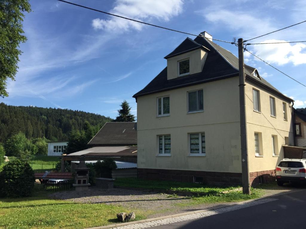 een wit huis met een zwart dak en een tuin bij Ferienwohnung Amanda in Stützerbach