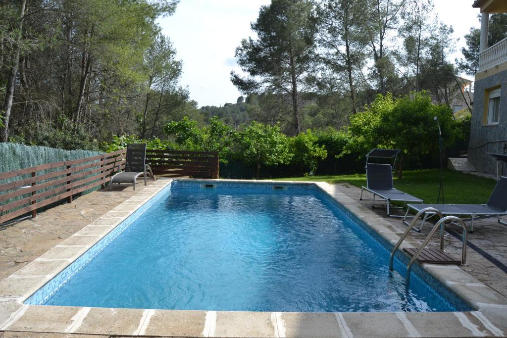 a swimming pool in a yard with two lawn chairs at Romani,26 in Olivella
