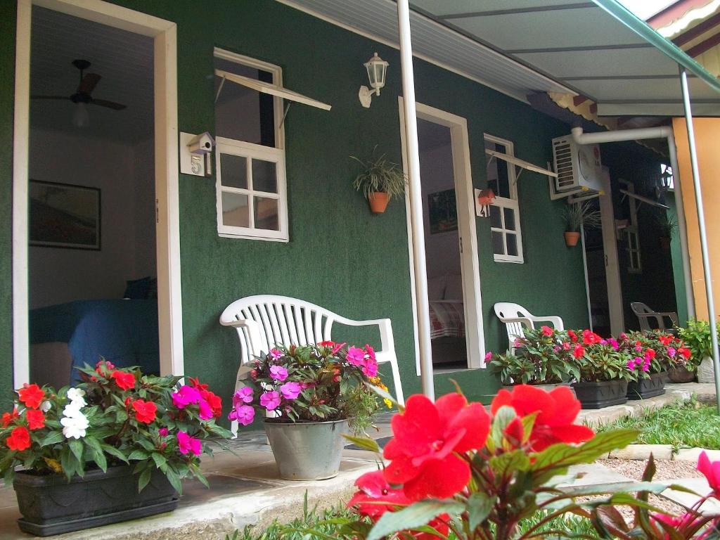 a green house with flowers on the porch at Hospedagem Da Laranjeira Gramado in Gramado