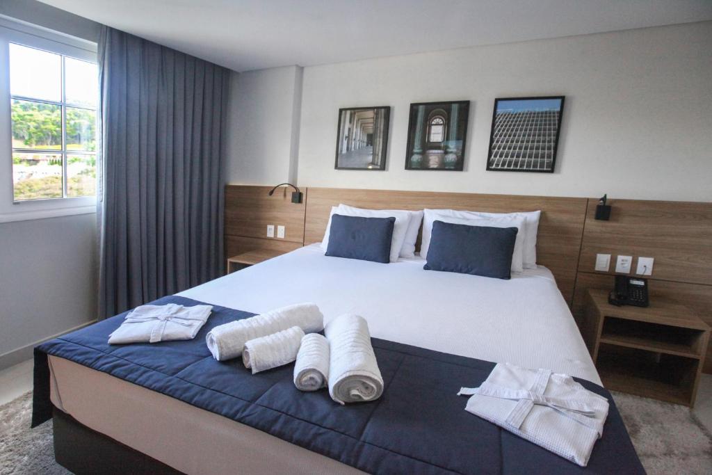 una camera da letto con un grande letto con asciugamani di Apto Itaipava Granja Brasil a Itaipava
